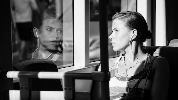 Sitting woman looking through window pane reflection